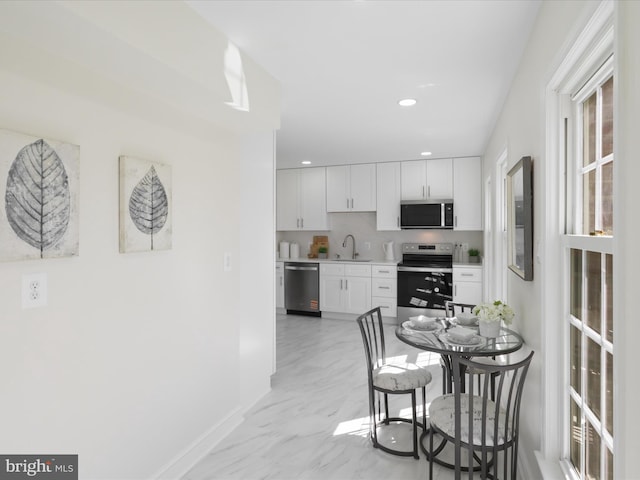 kitchen featuring recessed lighting, a sink, stainless steel appliances, light countertops, and white cabinets