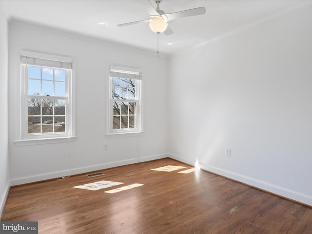 spare room featuring visible vents, a ceiling fan, baseboards, and wood finished floors