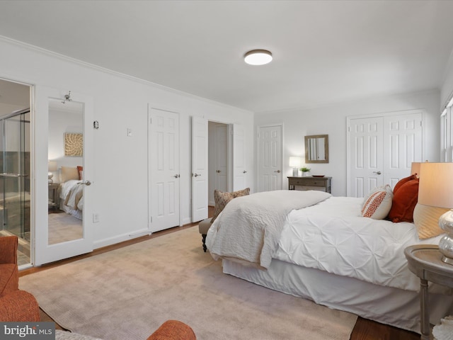 bedroom with crown molding, baseboards, and multiple closets