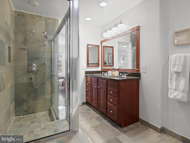 full bath featuring double vanity, baseboards, and a stall shower