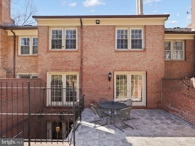 rear view of house with a patio area, french doors, brick siding, and fence