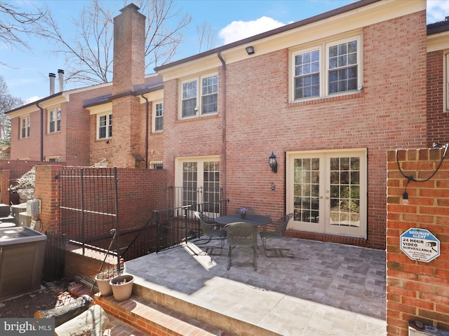 back of property with fence, french doors, brick siding, a chimney, and a patio area