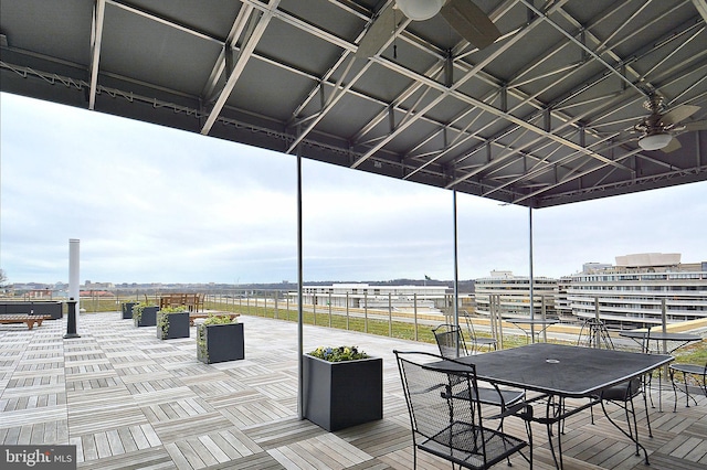 wooden deck featuring a view of city, outdoor dining area, and a ceiling fan