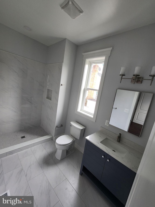 bathroom with vanity, toilet, tiled shower, visible vents, and marble finish floor