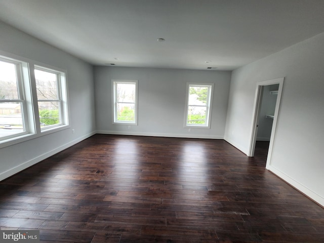 spare room with baseboards and dark wood finished floors