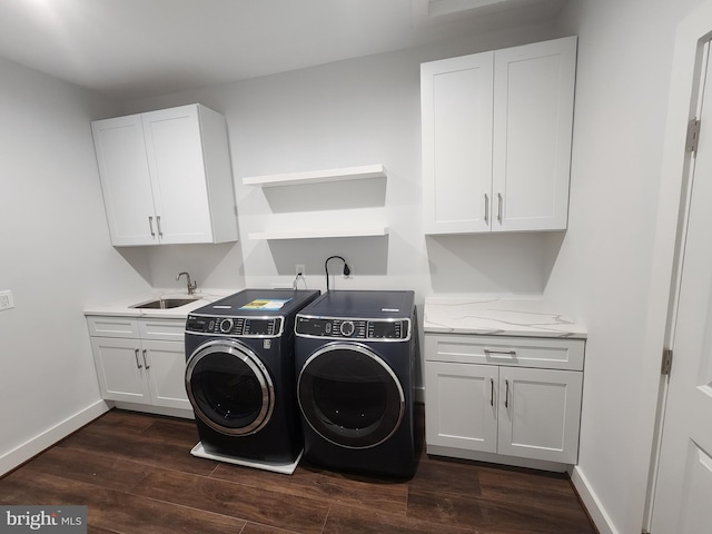 washroom featuring separate washer and dryer, baseboards, dark wood-type flooring, cabinet space, and a sink