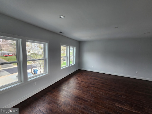 unfurnished room featuring dark wood-type flooring, baseboards, visible vents, and recessed lighting
