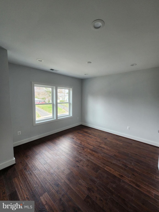 spare room with dark wood-style floors, baseboards, and visible vents