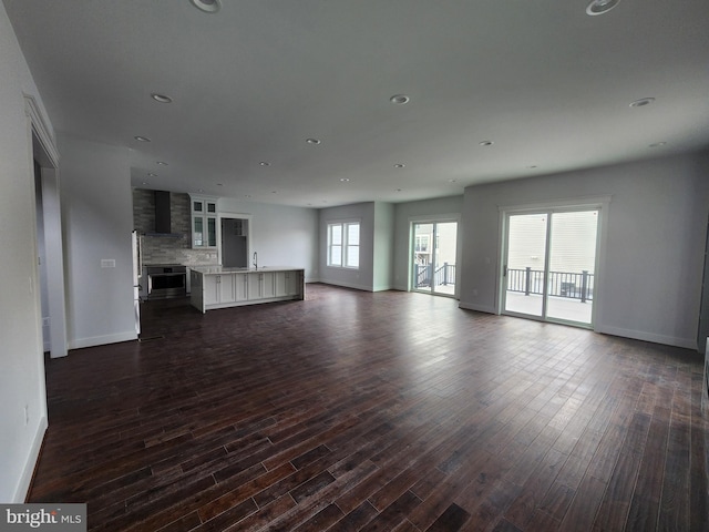 unfurnished living room with a sink, recessed lighting, and dark wood-type flooring