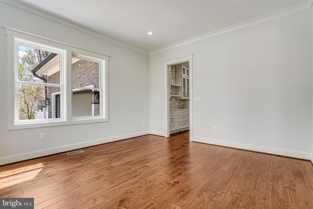 unfurnished room featuring crown molding, visible vents, recessed lighting, wood finished floors, and baseboards