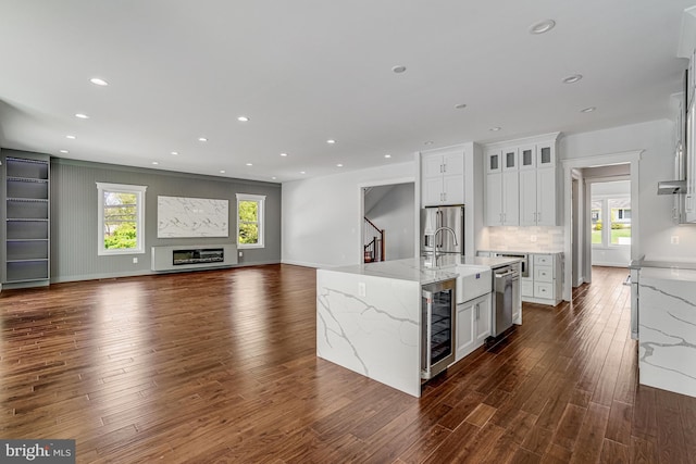 kitchen featuring tasteful backsplash, a sink, dark wood-style flooring, appliances with stainless steel finishes, and beverage cooler