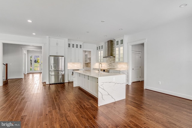 kitchen with backsplash, stainless steel fridge with ice dispenser, wall chimney exhaust hood, white cabinets, and dark wood-style floors