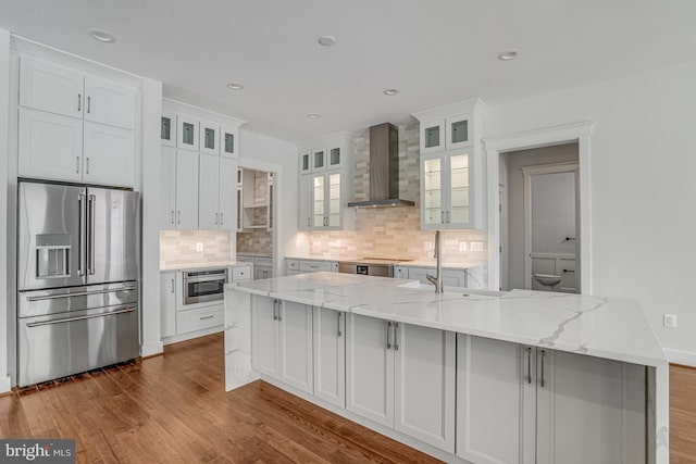 kitchen featuring tasteful backsplash, wall chimney range hood, white cabinets, stainless steel appliances, and dark wood-style floors