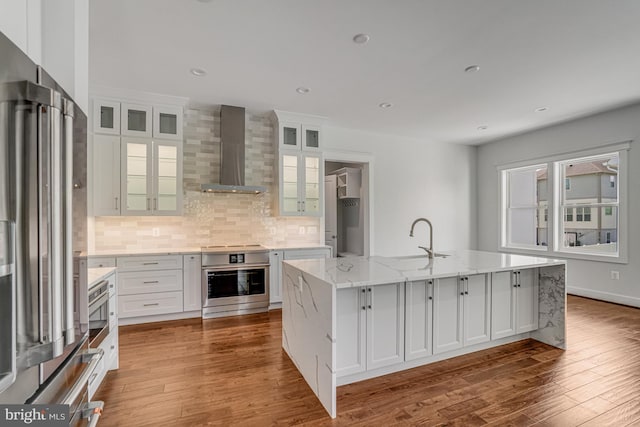 kitchen featuring range, wall chimney range hood, freestanding refrigerator, backsplash, and a sink