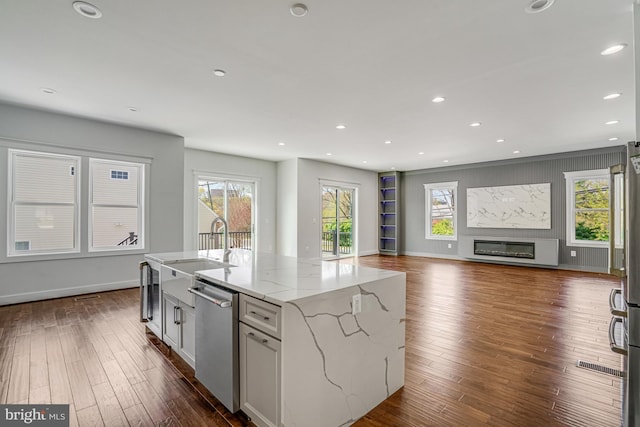 kitchen featuring light stone counters, stainless steel dishwasher, recessed lighting, and dark wood-style flooring