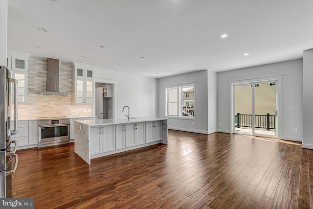 kitchen featuring tasteful backsplash, wall chimney range hood, white cabinetry, dark wood-type flooring, and stove