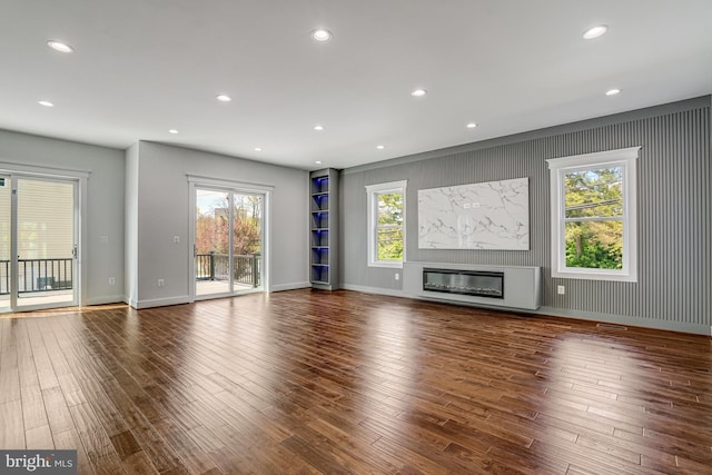 unfurnished living room featuring wood finished floors, a glass covered fireplace, and recessed lighting
