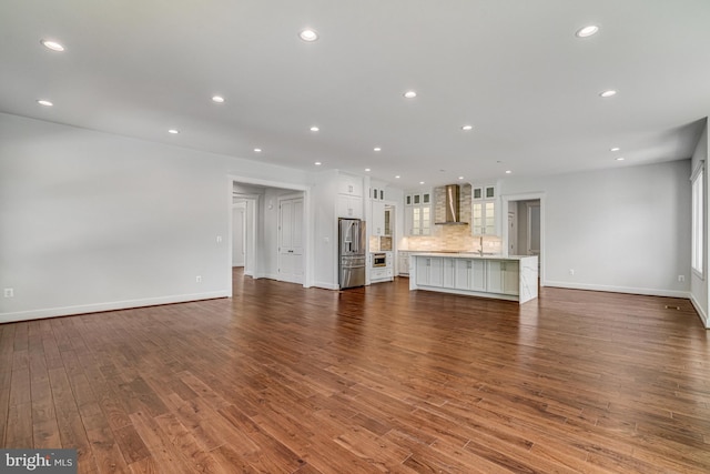unfurnished living room featuring baseboards, recessed lighting, dark wood-type flooring, a healthy amount of sunlight, and a sink