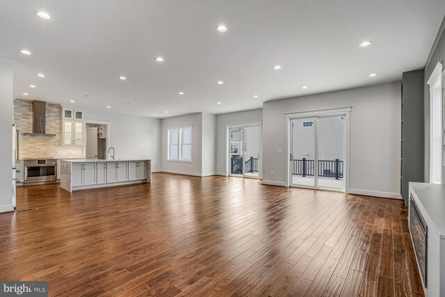 unfurnished living room with a sink, dark wood-style floors, baseboards, and recessed lighting
