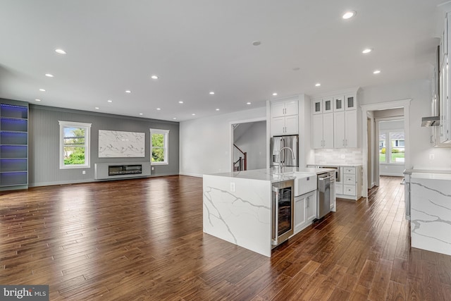 kitchen with stainless steel appliances, dark wood-style floors, beverage cooler, and a sink