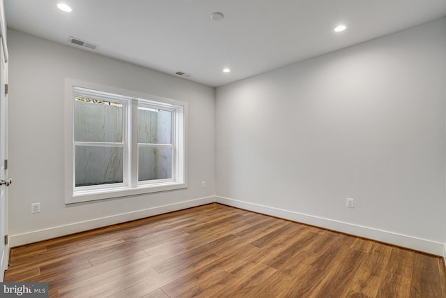empty room with visible vents, baseboards, and wood finished floors