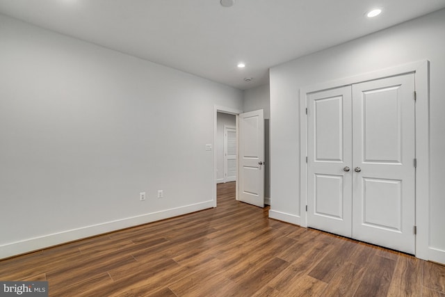 unfurnished bedroom featuring a closet, recessed lighting, baseboards, and wood finished floors
