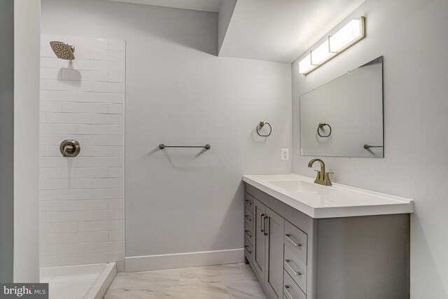 full bathroom with a tile shower, marble finish floor, vanity, and baseboards