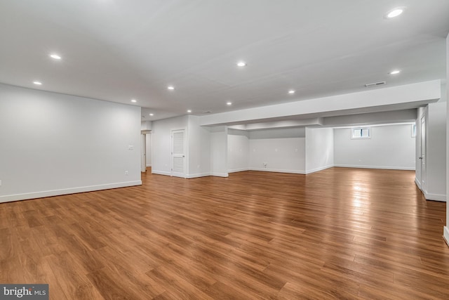 below grade area with light wood finished floors, baseboards, visible vents, and recessed lighting