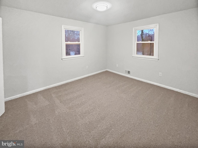 carpeted spare room featuring baseboards and visible vents