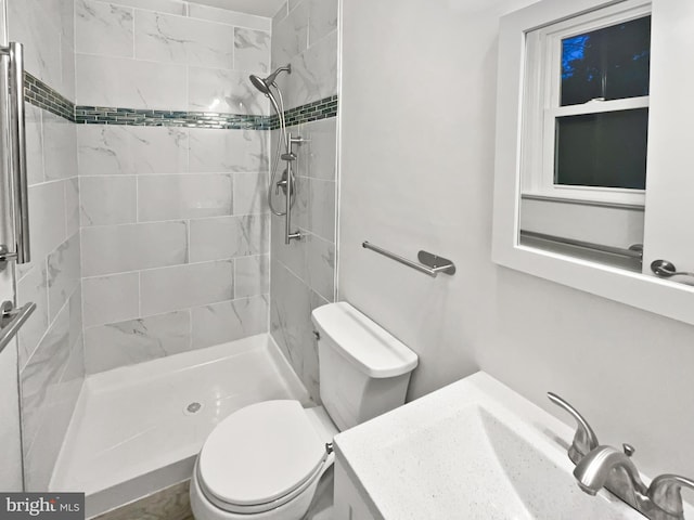 bathroom featuring tiled shower, toilet, and vanity