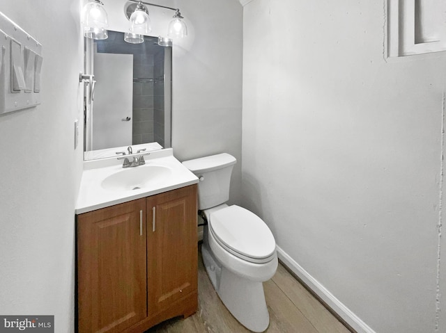 bathroom with vanity, toilet, wood finished floors, and baseboards