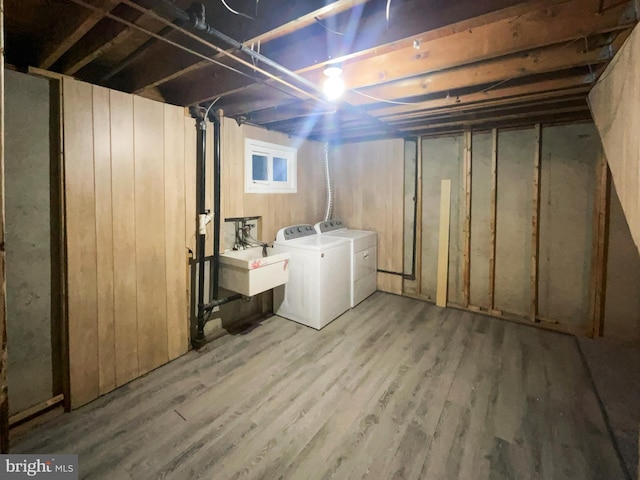 unfinished basement with a sink, independent washer and dryer, and wood finished floors