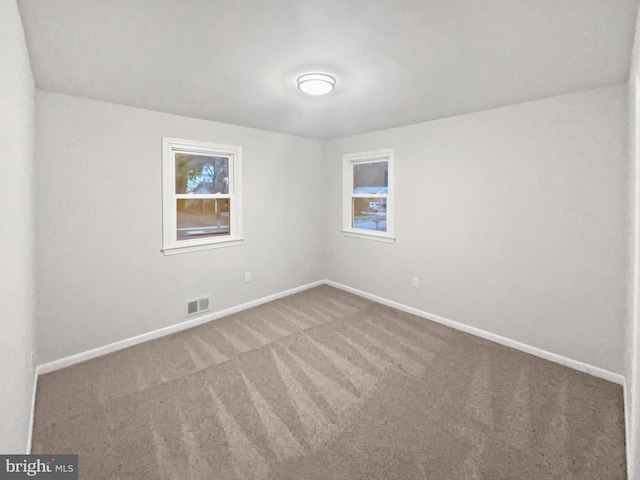 spare room with visible vents, baseboards, and carpet flooring