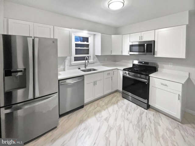 kitchen with white cabinets, stainless steel appliances, light countertops, and a sink