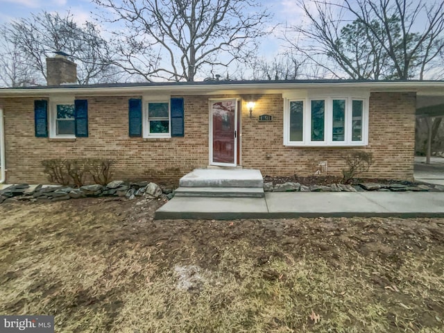 single story home featuring brick siding and a chimney