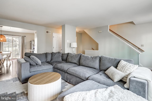 living room featuring stairway, light wood-style floors, and visible vents