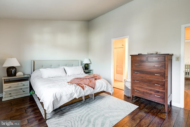 bedroom featuring dark wood finished floors, baseboards, and connected bathroom