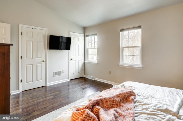 bedroom with visible vents, lofted ceiling, baseboards, and dark wood finished floors