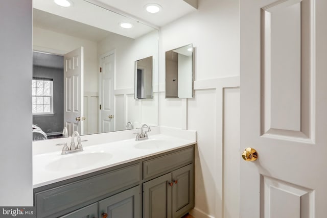 ensuite bathroom with a sink, ensuite bathroom, recessed lighting, and double vanity