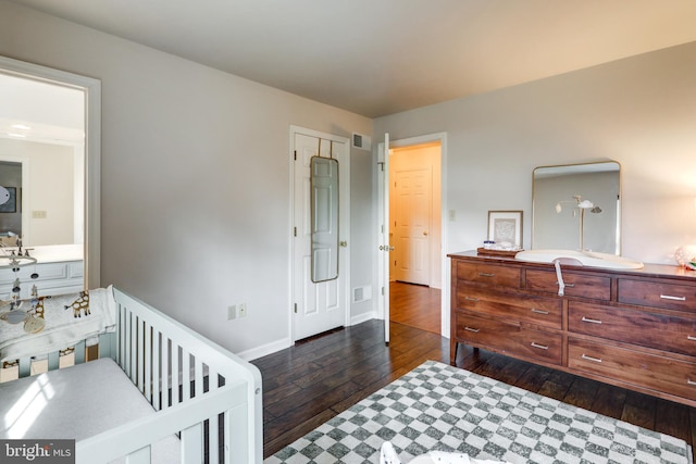 bedroom with dark wood-type flooring, baseboards, visible vents, and a sink