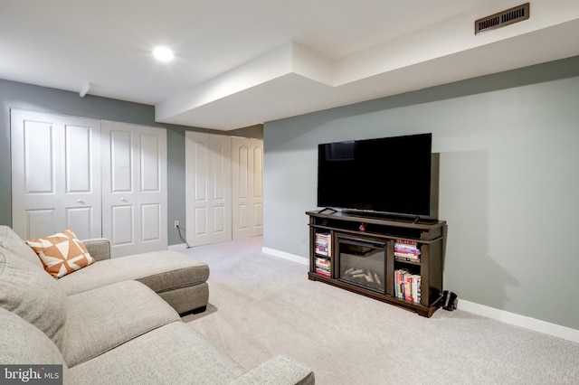 carpeted living area with baseboards and visible vents