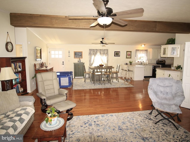 living area with lofted ceiling with beams, dark wood finished floors, and ceiling fan