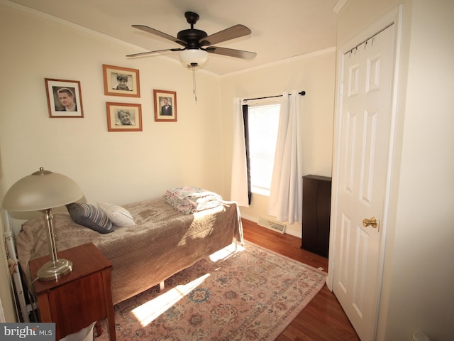 bedroom featuring visible vents, ornamental molding, ceiling fan, and dark wood-style flooring