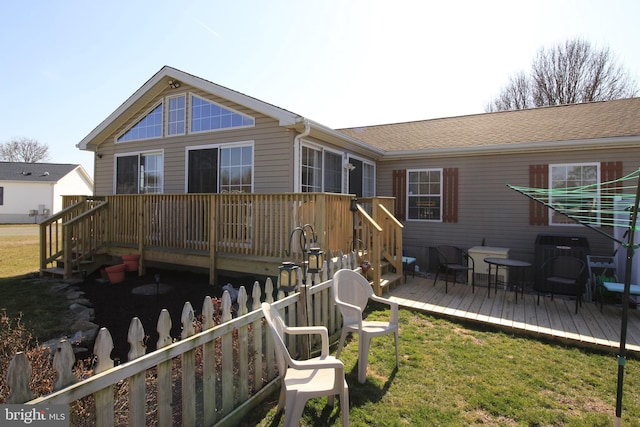 back of property featuring a shingled roof, a yard, and a wooden deck