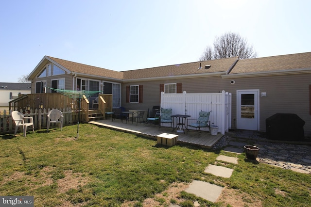 rear view of house with fence, a lawn, and a wooden deck