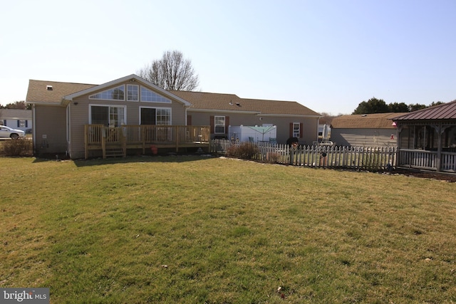 back of property featuring a lawn, a deck, and fence