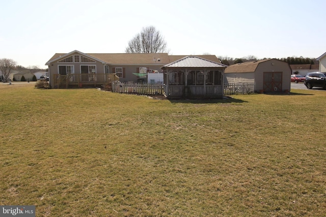 view of yard with an outbuilding, a wooden deck, a storage shed, and fence