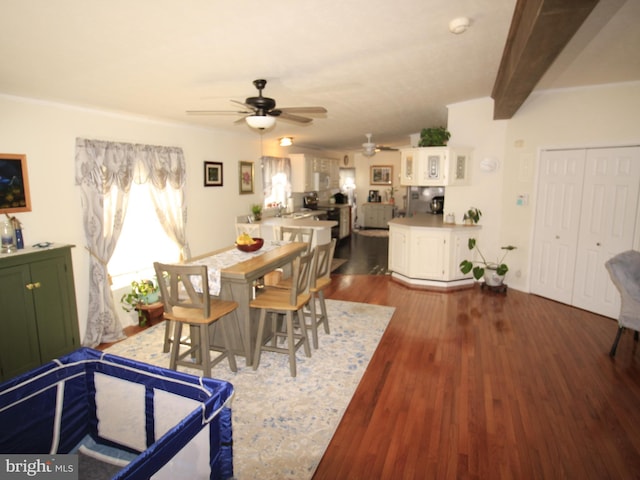 dining space featuring beam ceiling, wood finished floors, and a ceiling fan