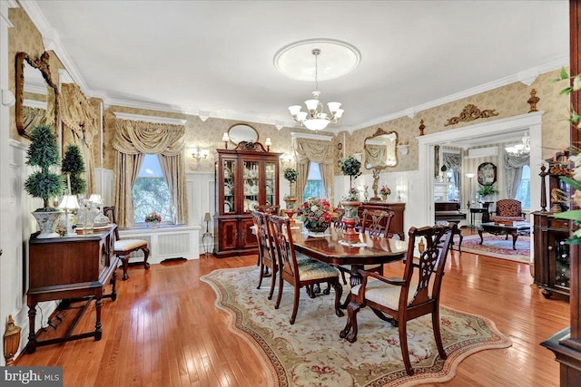 dining room featuring hardwood / wood-style flooring, radiator, crown molding, wallpapered walls, and a chandelier