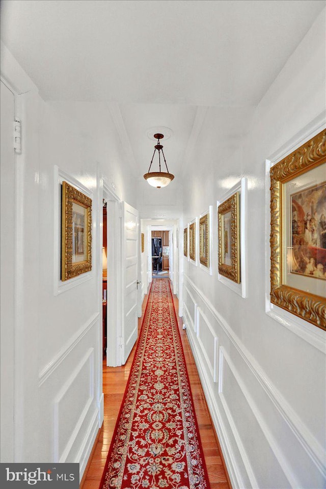 corridor featuring a decorative wall and light wood finished floors